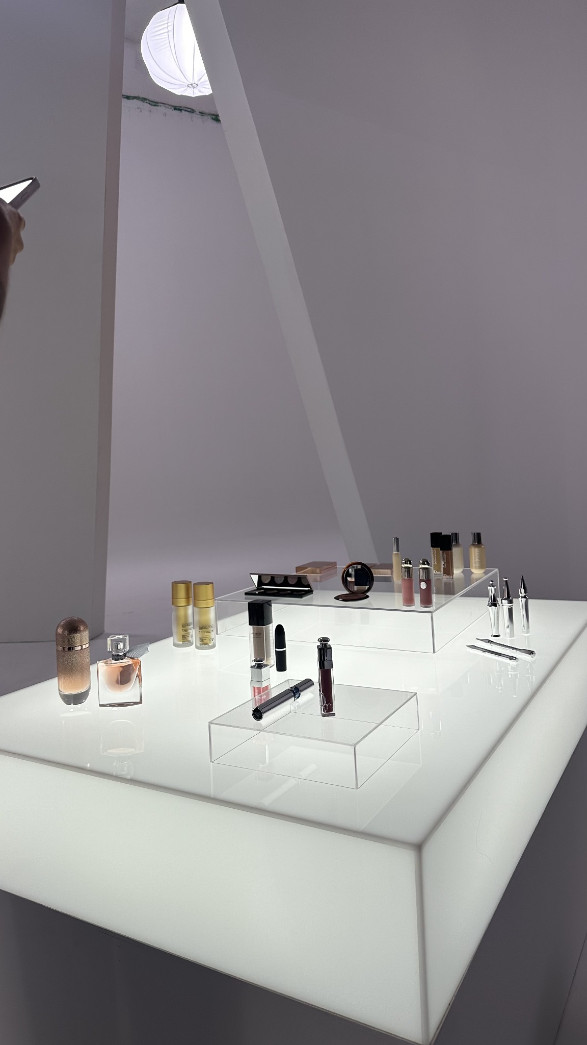 Bodegón de productos de belleza sobre una mesa iluminada y bases de acrílico en un estudio fotográfico